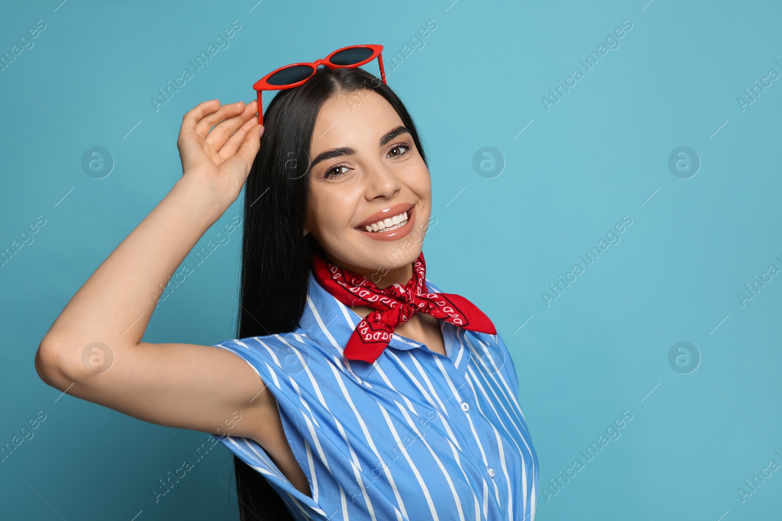 Photo of Fashionable young woman in stylish outfit with bandana on light blue background, space for text