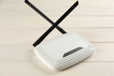 Modern Wi-Fi router on white wooden background