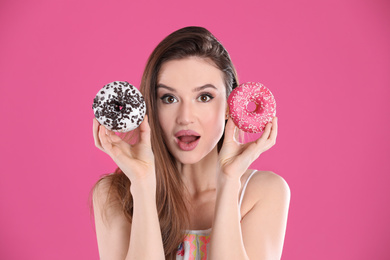 Photo of Beautiful young woman with donuts on pink background
