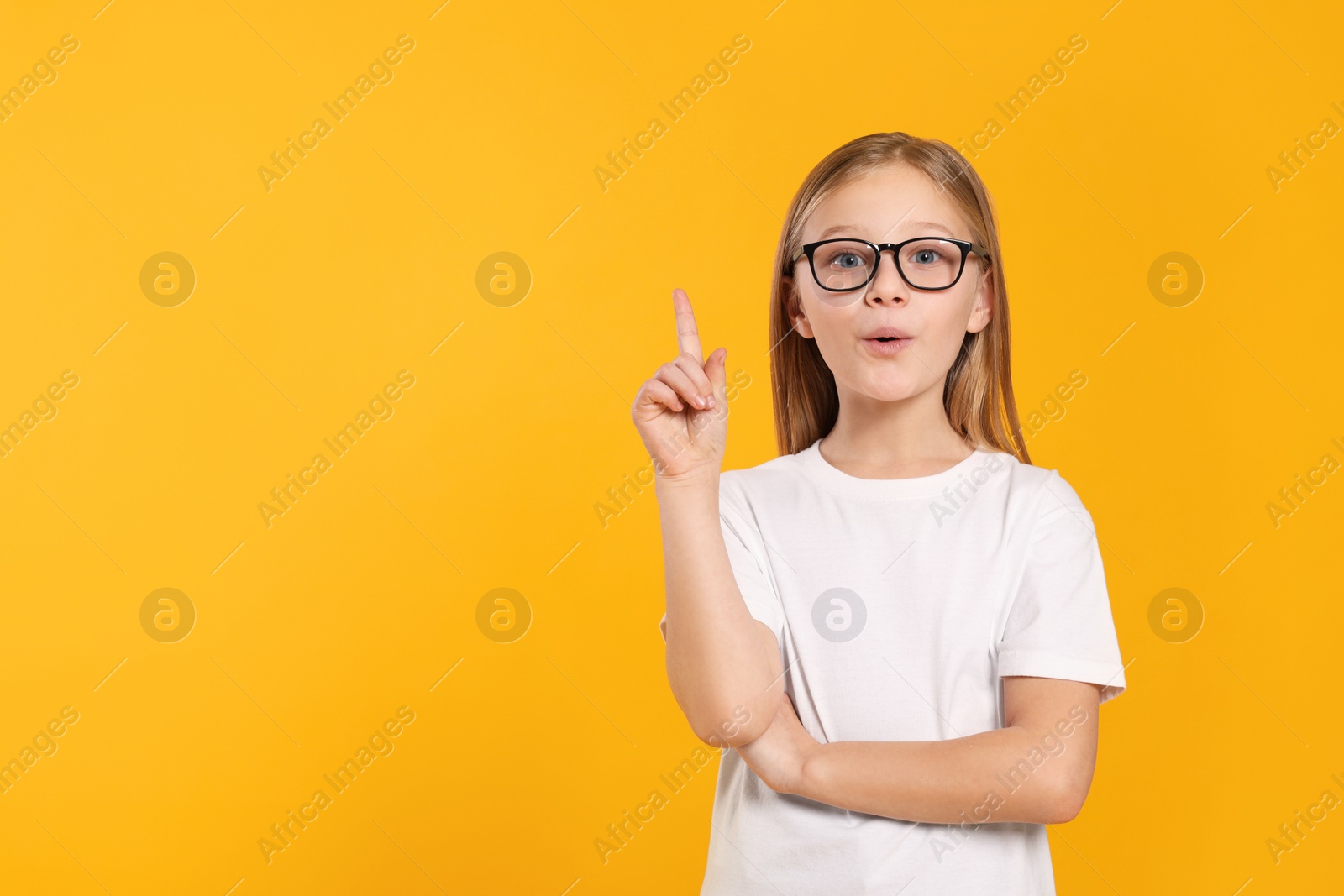 Photo of Portrait of emotional girl in glasses on orange background. Space for text