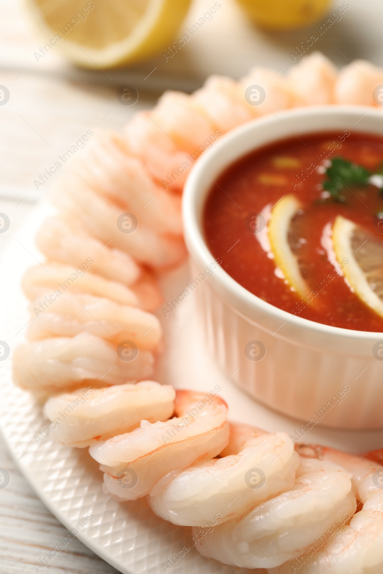 Photo of Tasty boiled shrimps with cocktail sauce and lemon on plate, closeup