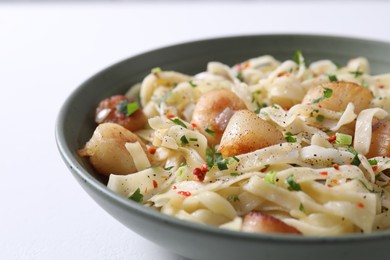 Delicious scallop pasta with spices in bowl on white table, closeup