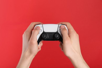 Photo of Man using wireless game controller on red background, closeup