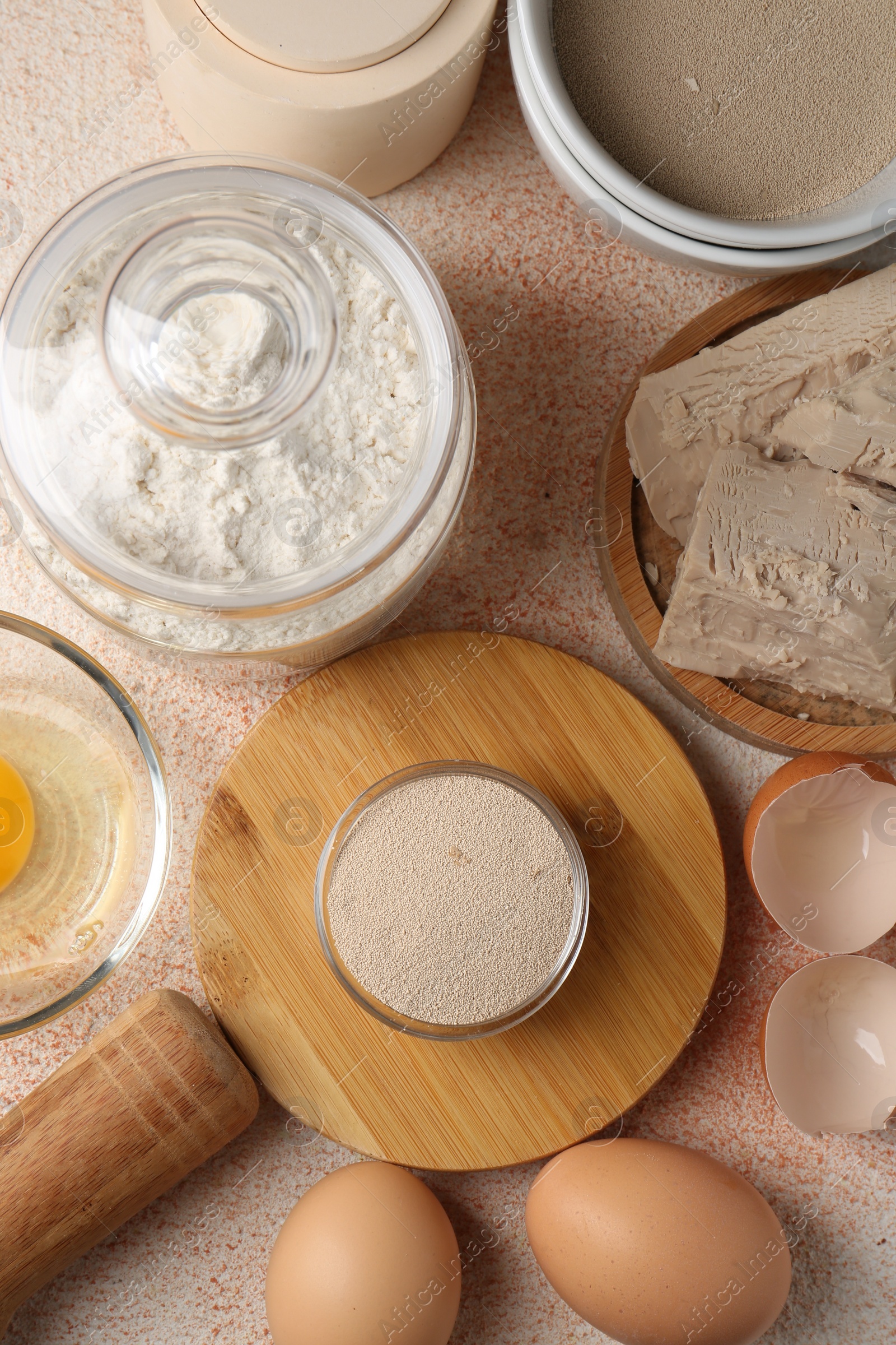 Photo of Different types of yeast, flour and eggs on orange textured table, flat lay