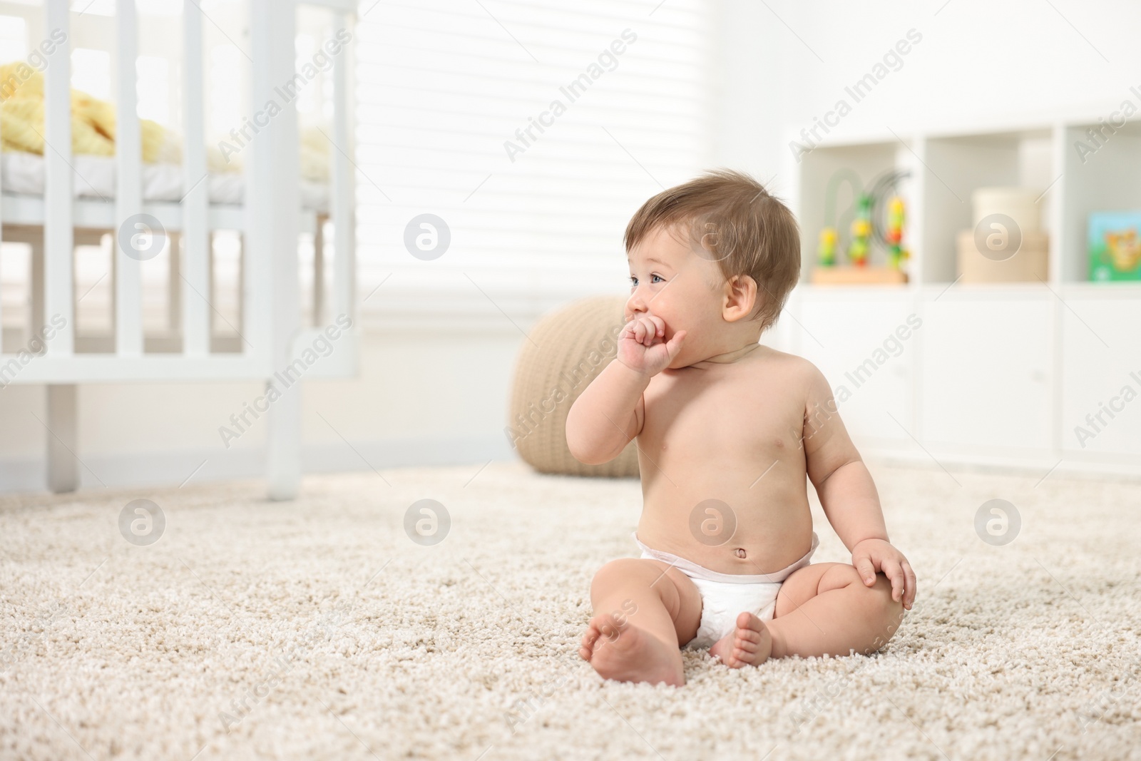 Photo of Cute baby boy sitting on carpet at home. Space for text