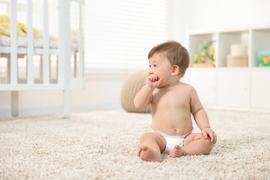 Photo of Cute baby boy sitting on carpet at home. Space for text