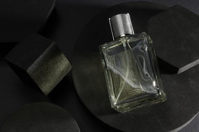 Photo of Stylish presentation of luxury men`s perfume in bottle on black background, top view. Space for text