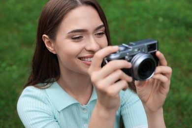 Photo of Young woman with camera taking photo outdoors. Interesting hobby