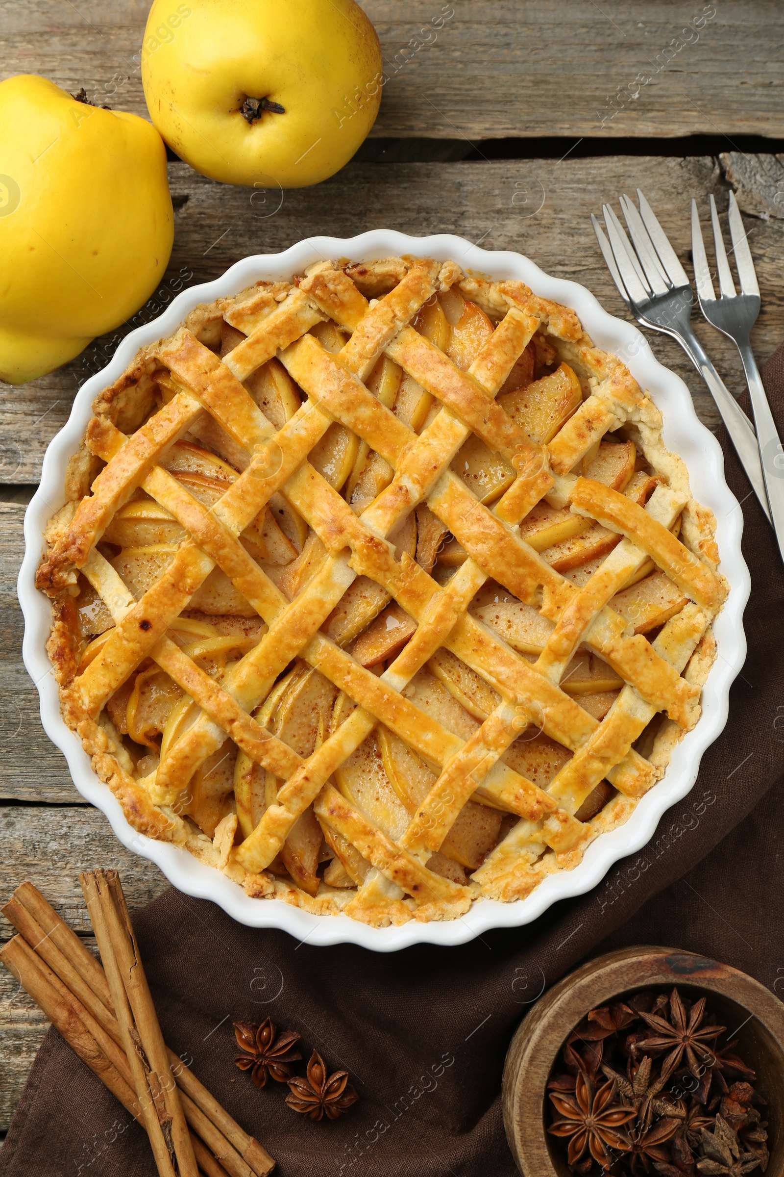 Photo of Tasty homemade quince pie served on wooden table, flat lay