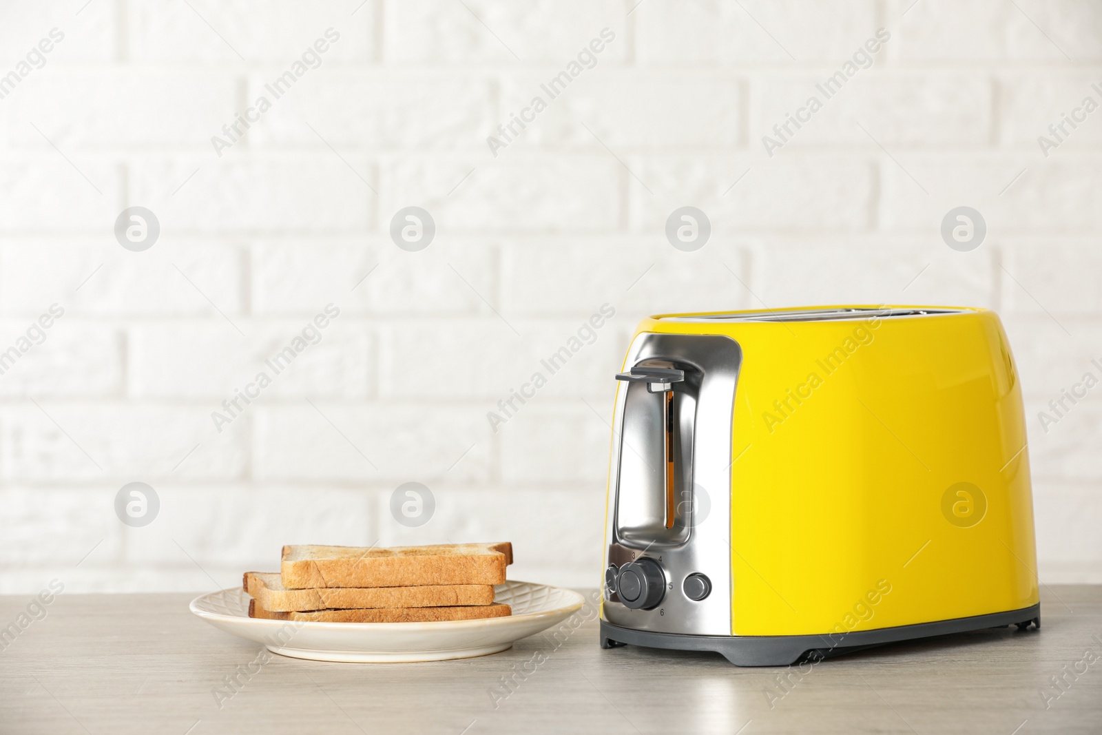 Photo of Electric toaster with bread slices on wooden table. Space for text