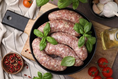 Photo of Raw homemade sausages and different products on grey table, flat lay