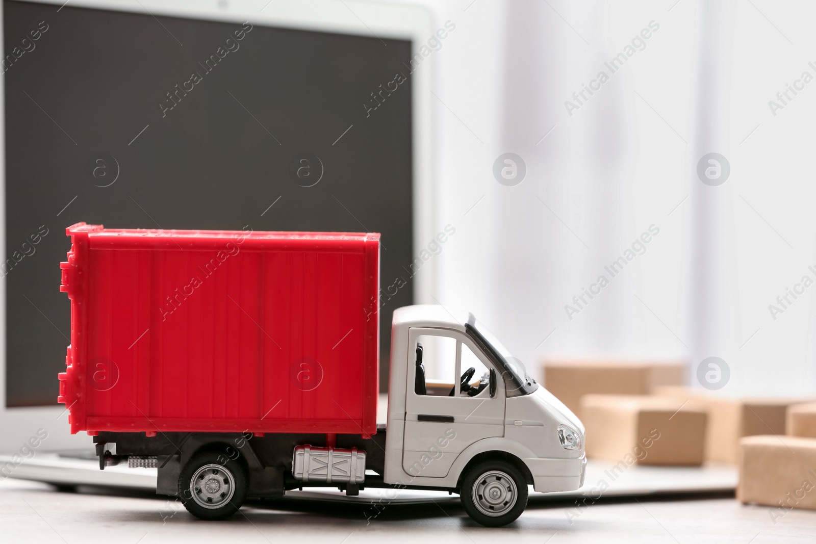 Photo of Toy truck near laptop on table. Logistics and wholesale concept