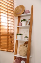 Stylish room interior with wooden ladder near white wall