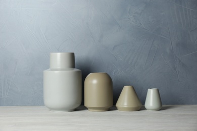 Photo of Beautiful ceramic vases on table against color wall. Space for text