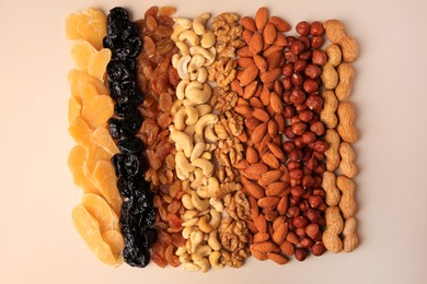 Mix of delicious dried nuts and fruits on beige background, flat lay