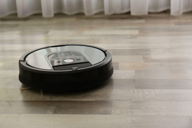 Photo of Modern robotic vacuum cleaner on wooden floor indoors