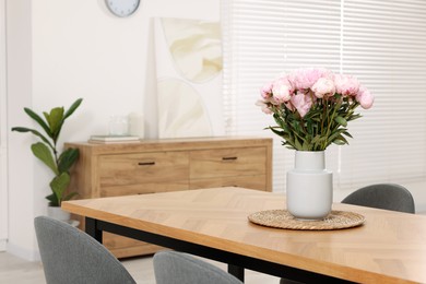 Photo of Vase with pink peonies on wooden table in dining room