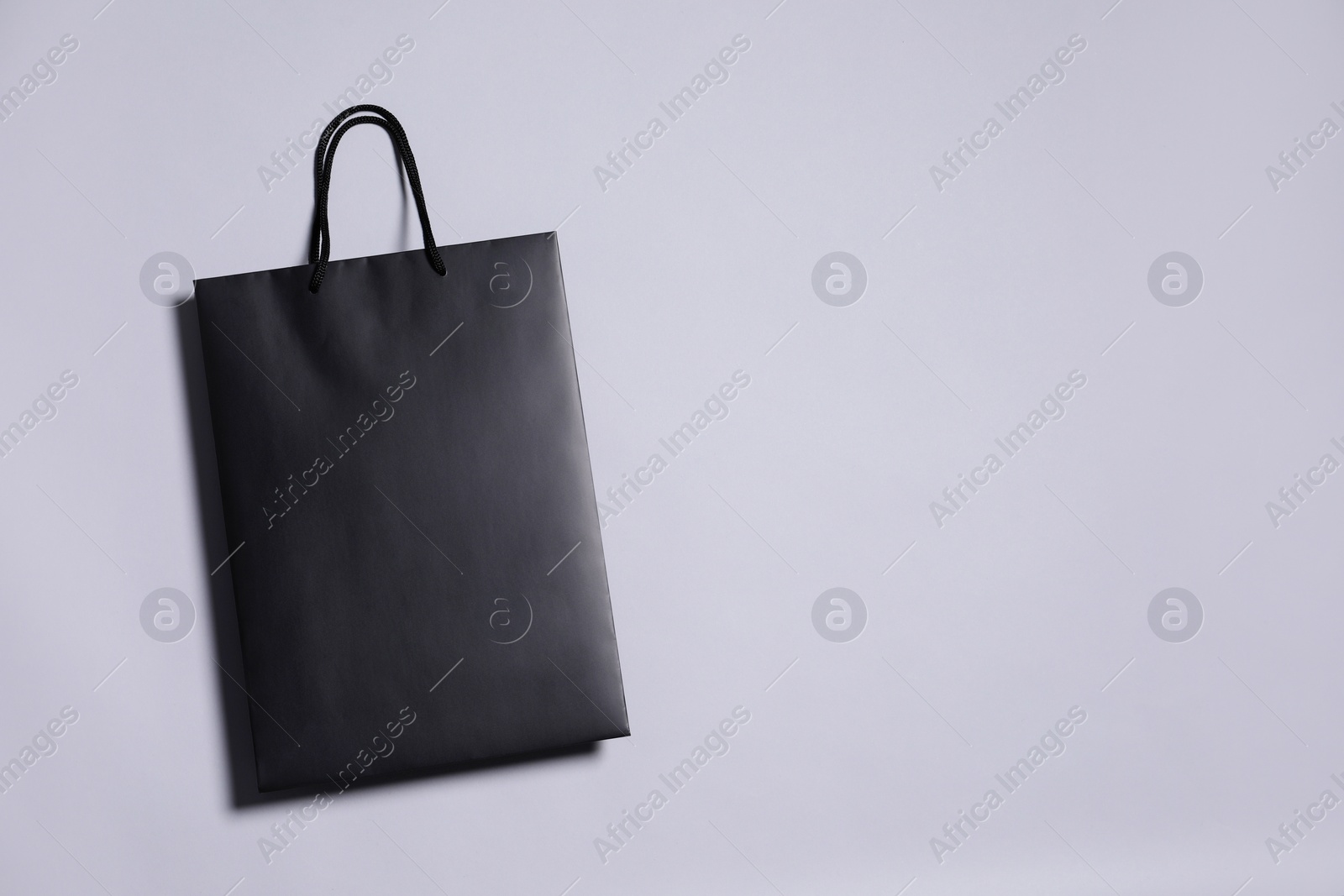 Photo of One black paper shopping bag on grey background, top view. Space for text