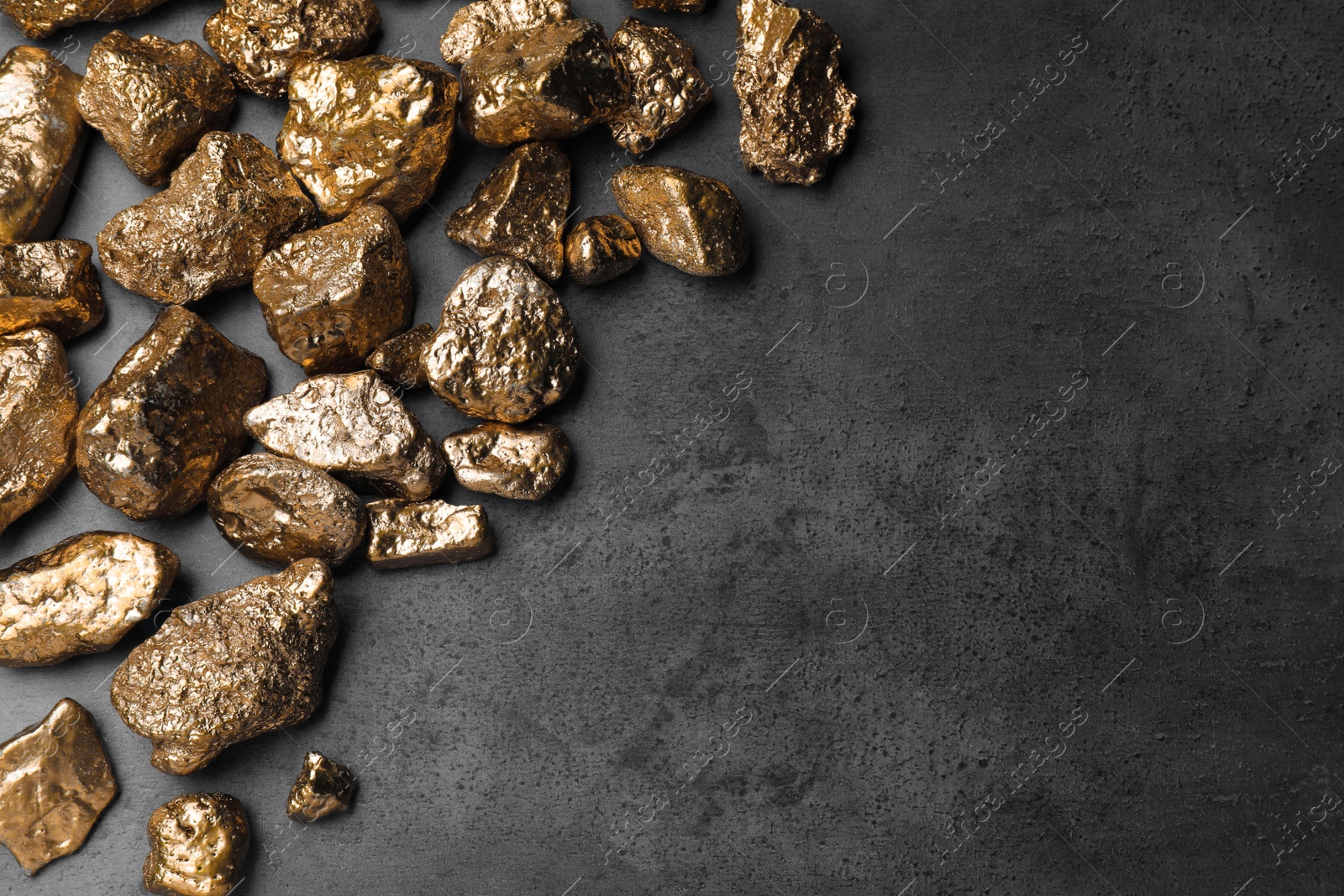 Photo of Pile of gold nuggets on grey table, flat lay. Space for text