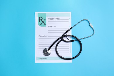 Photo of Clipboard with medical prescription form and stethoscope on light blue background, flat lay