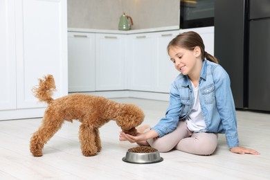 Little child feeding cute puppy in kitchen. Lovely pet