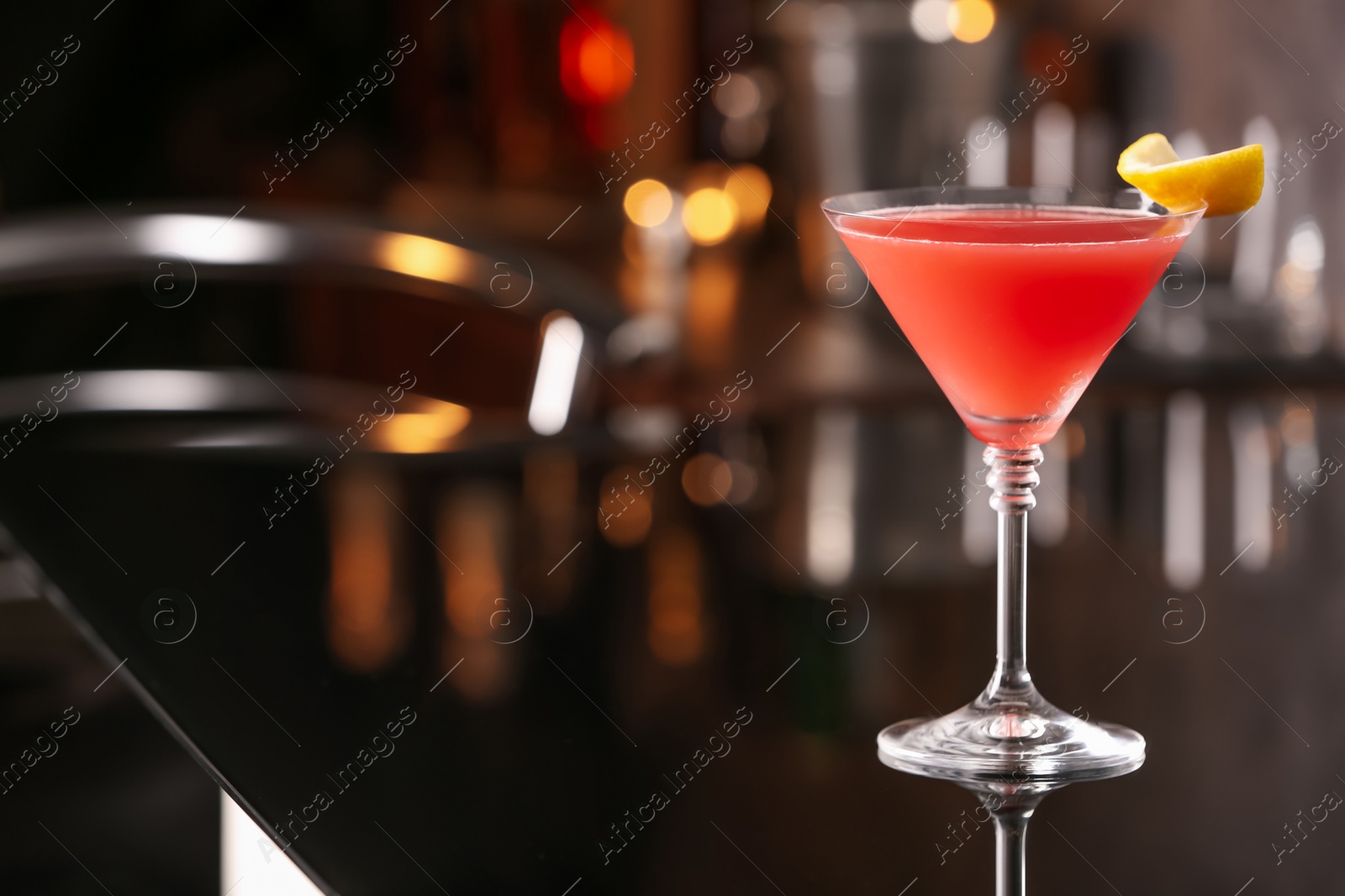 Photo of Cosmopolitan cocktail on black table in bar. Space for text