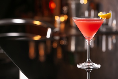 Photo of Cosmopolitan cocktail on black table in bar. Space for text