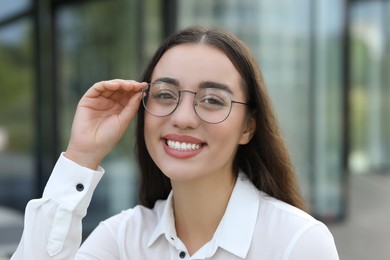 Photo of Portrait of beautiful woman in glasses outdoors. Attractive lady smiling and looking into camera
