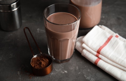 Glass with tasty chocolate milk on gray table. Dairy drink