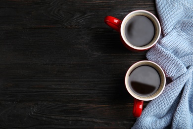 Photo of Flat lay composition cups of hot coffee and sweater on black wooden background, space for text. Winter drink