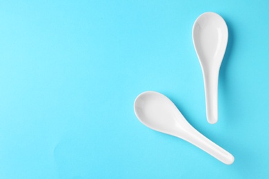 Miso soup spoons on blue background, flat lay. Space for text