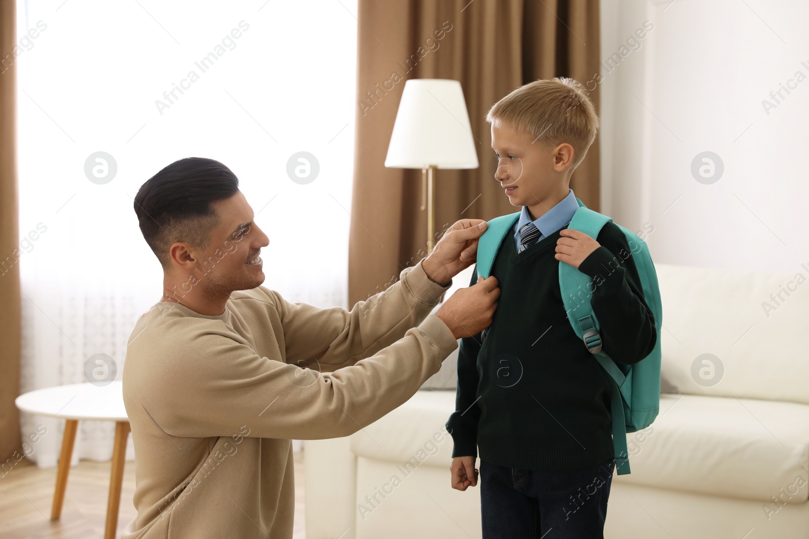 Photo of Father helping his little child get ready for school at home