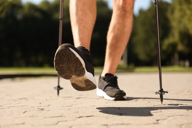 Man practicing Nordic walking with poles outdoors on sunny day, closeup