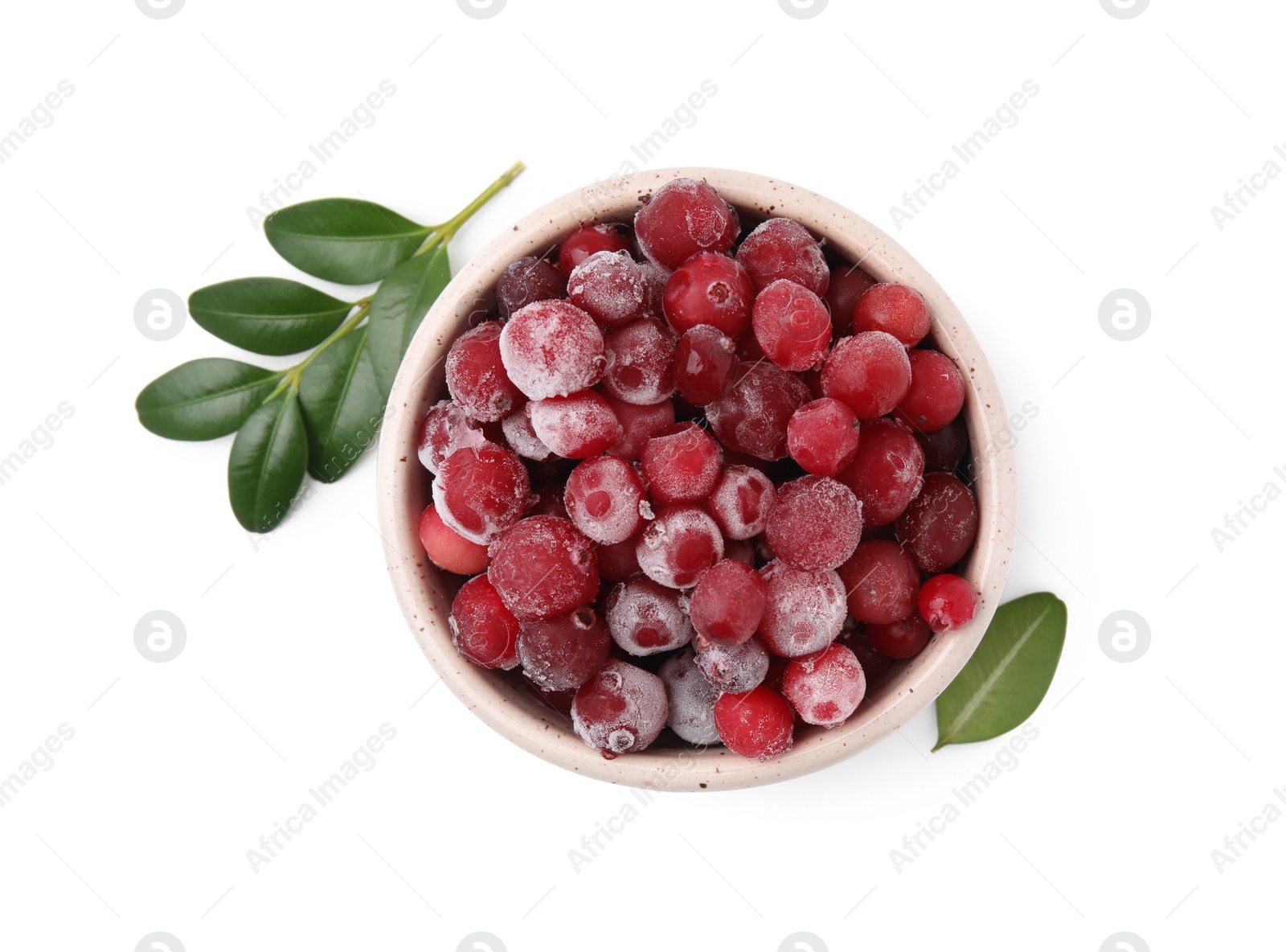 Photo of Frozen red cranberries in bowl and green leaves isolated on white, top view