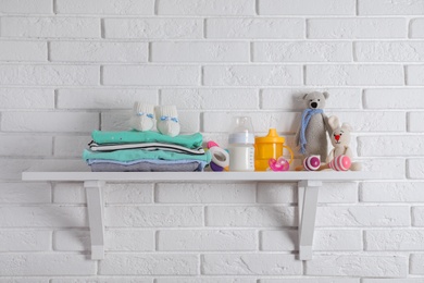 Shelf with baby accessories on white brick wall
