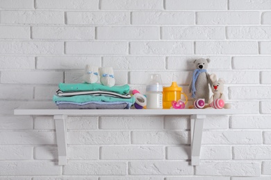 Photo of Shelf with baby accessories on white brick wall