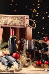 Bottles of wine, glass, wooden boxes, corks and red Christmas balls on table