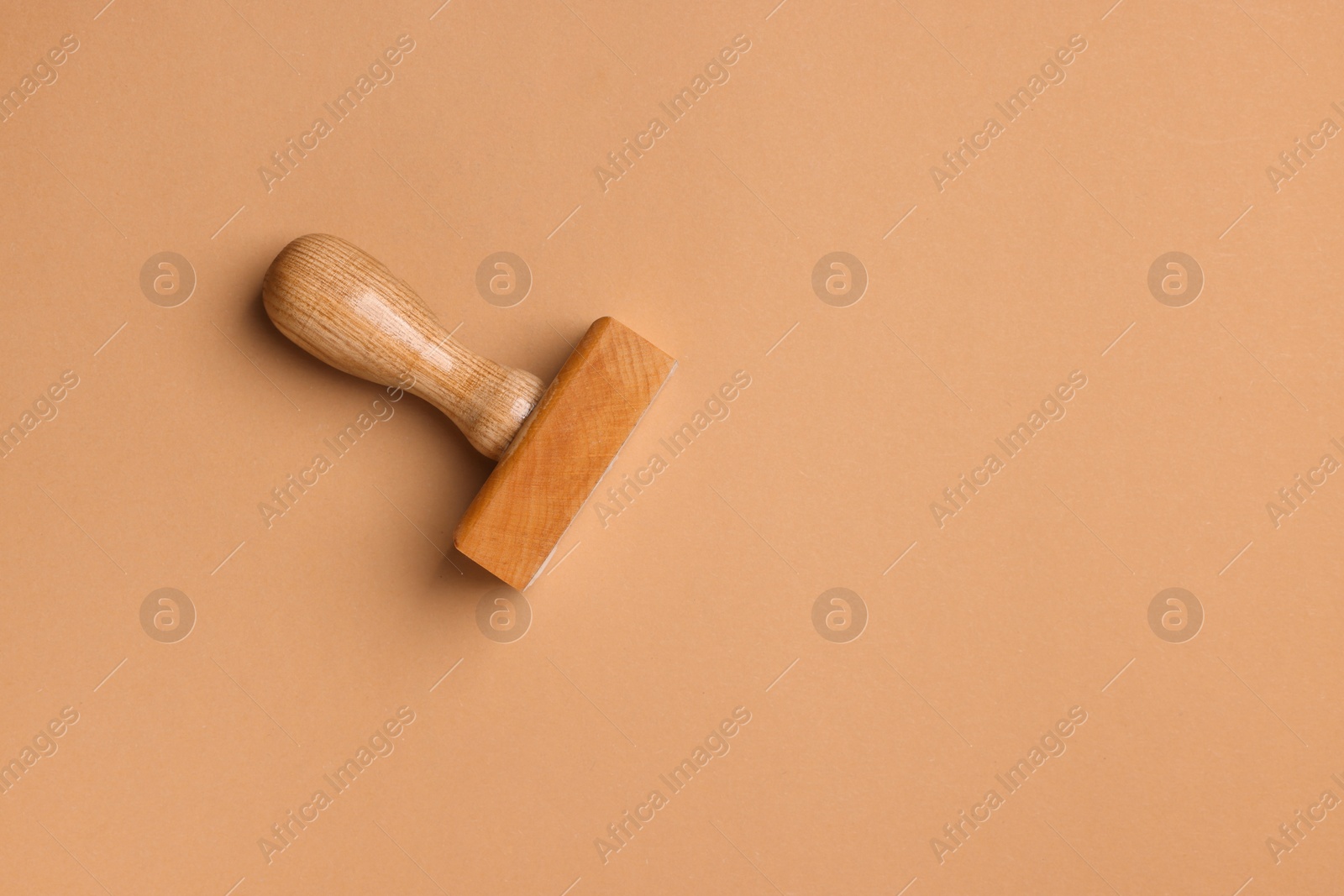 Photo of One wooden stamp tool on light brown background, top view. Space for text