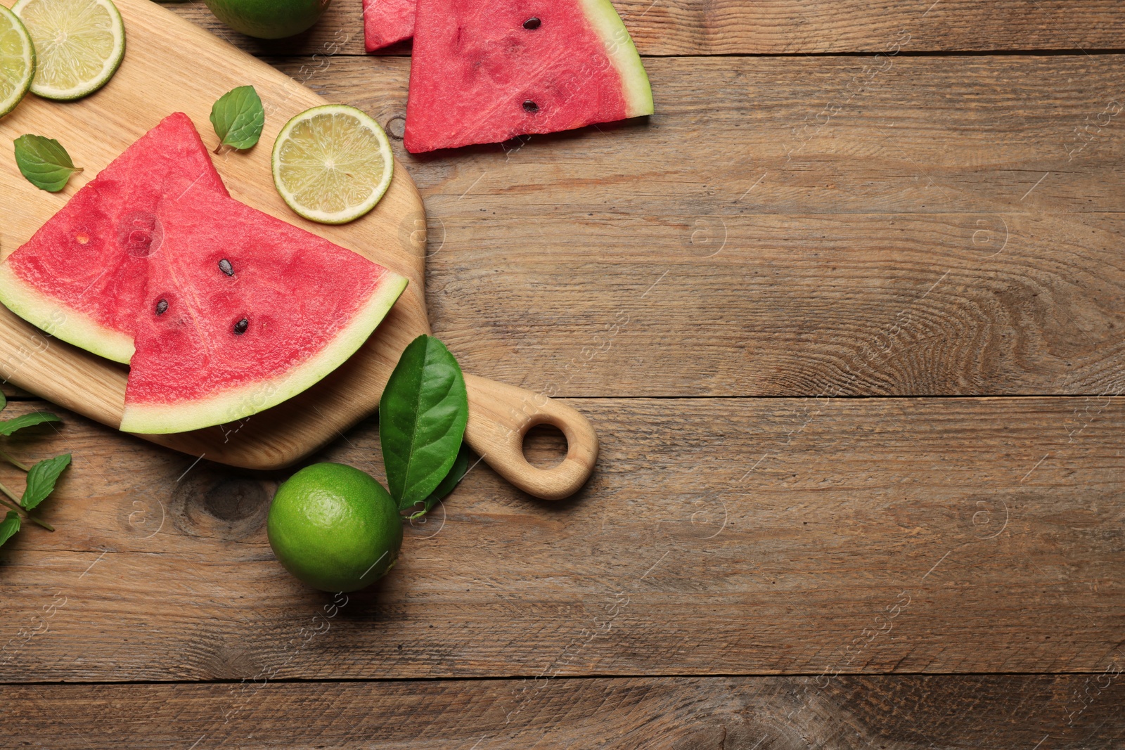 Photo of Tasty sliced watermelon and limes on wooden table, flat lay. Space for text
