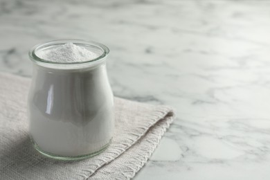 Baking powder in jar on white marble table, space for text