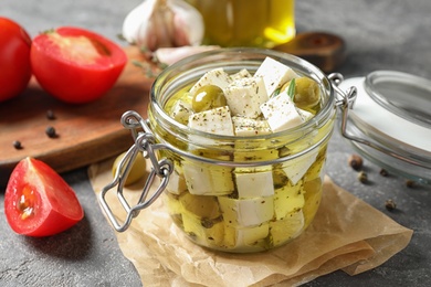 Photo of Composition with pickled feta cheese in jar on grey table