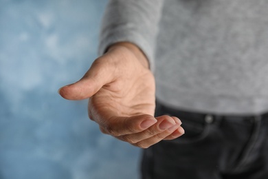 Woman offering helping hand on color background, closeup