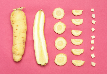 Whole and cut raw white carrots on pink background, flat lay