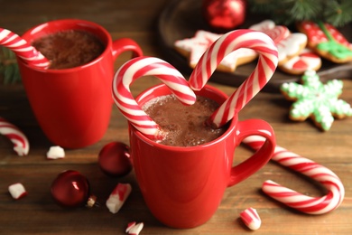 Cup of hot chocolate with Christmas candy canes on wooden table