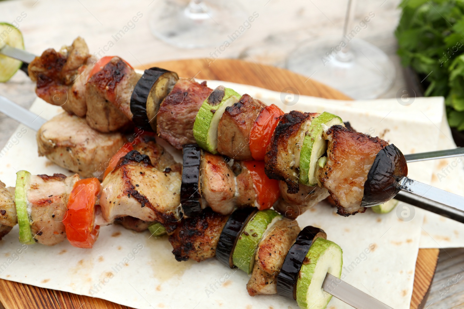 Photo of Metal skewers with delicious meat and vegetables served on wooden table, closeup