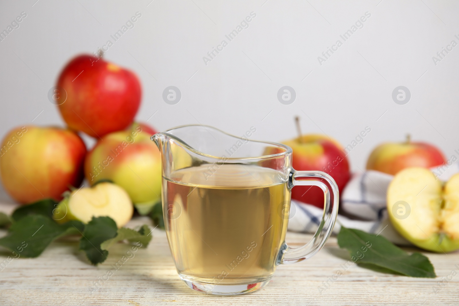 Photo of Natural apple vinegar and fresh fruits on white wooden table. Space for text