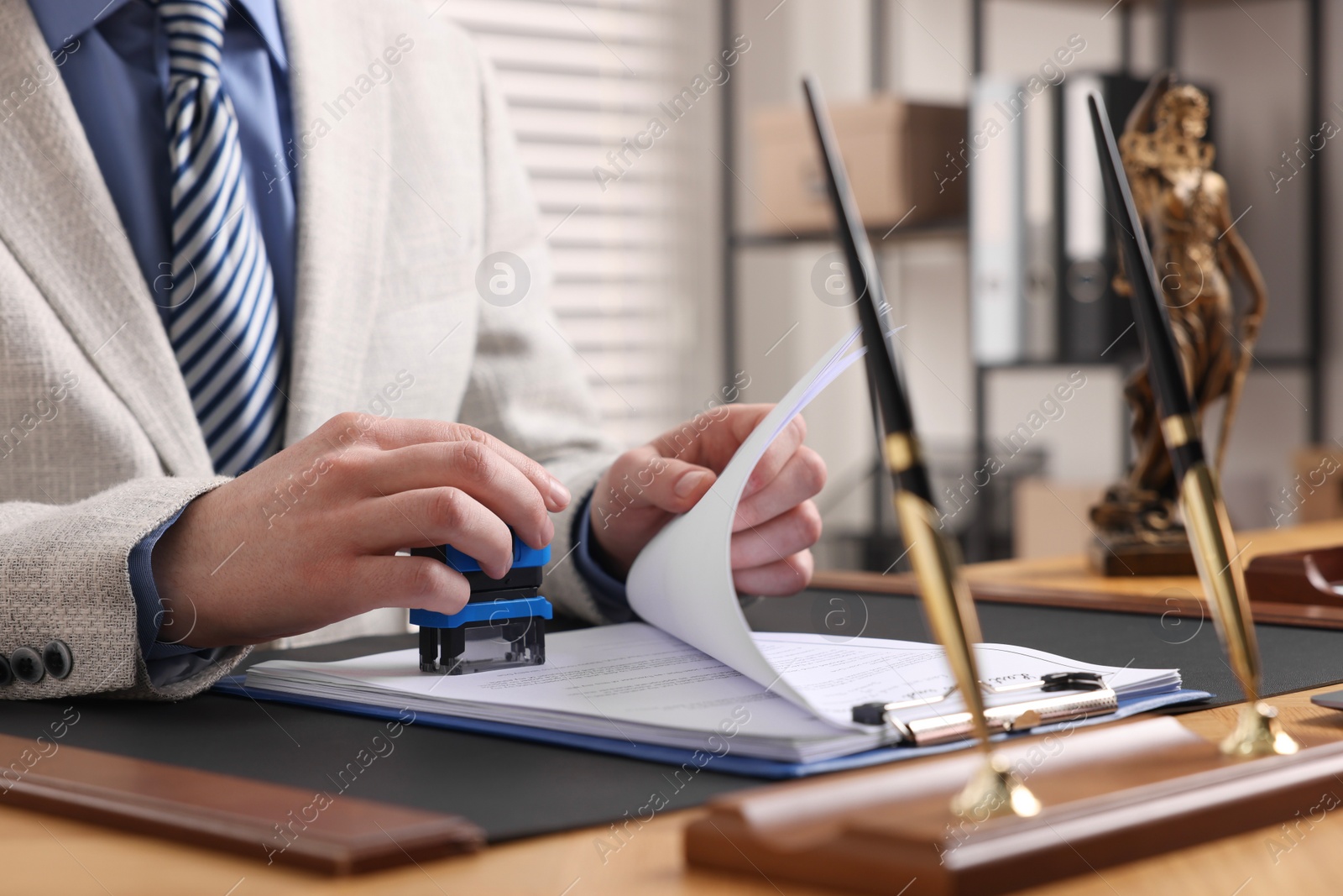 Photo of Notary stamping document at table in office, closeup