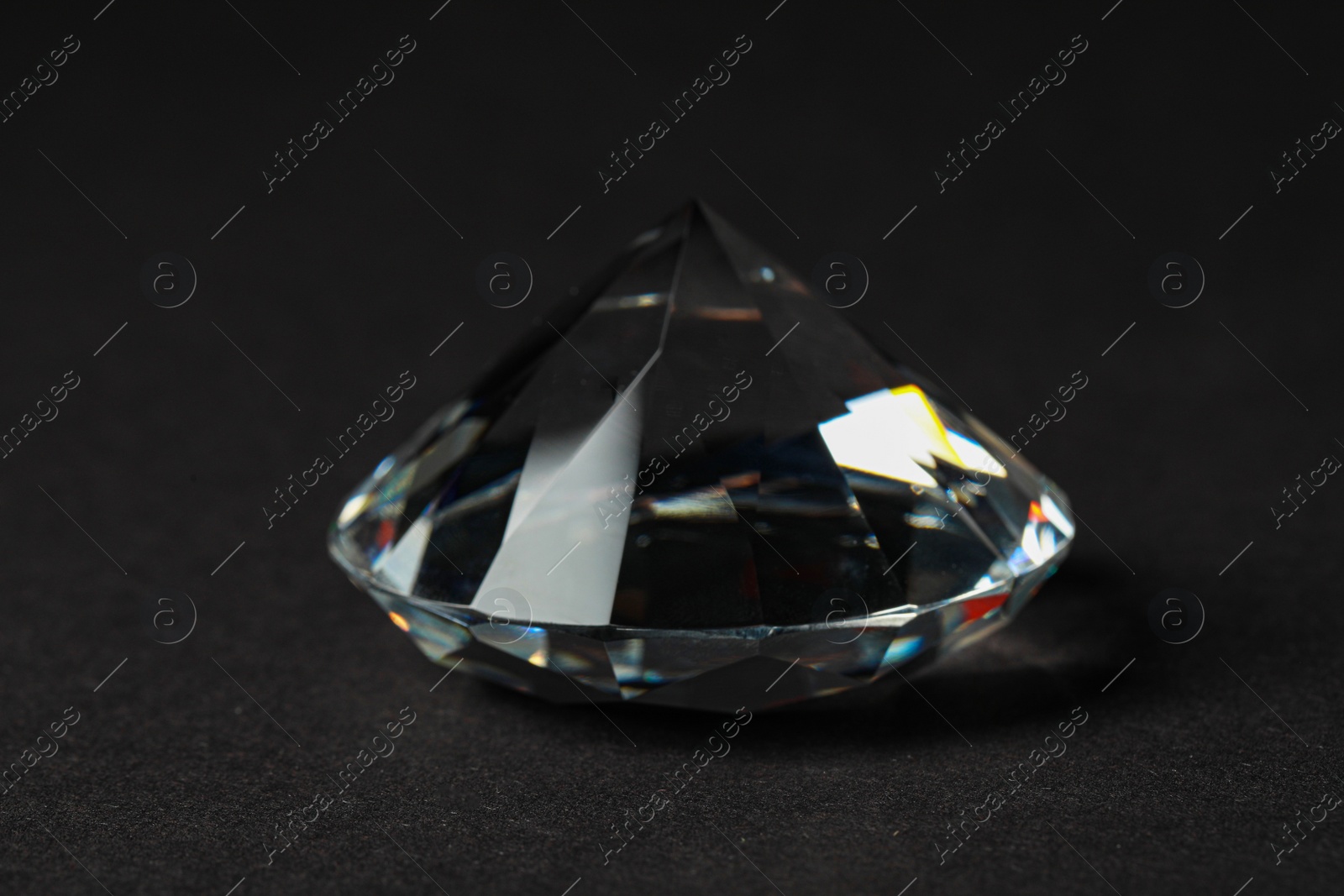 Photo of Beautiful dazzling diamond on dark background, closeup. Precious gemstone