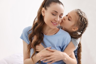 Photo of Cute daughter kissing and hugging her mom indoors