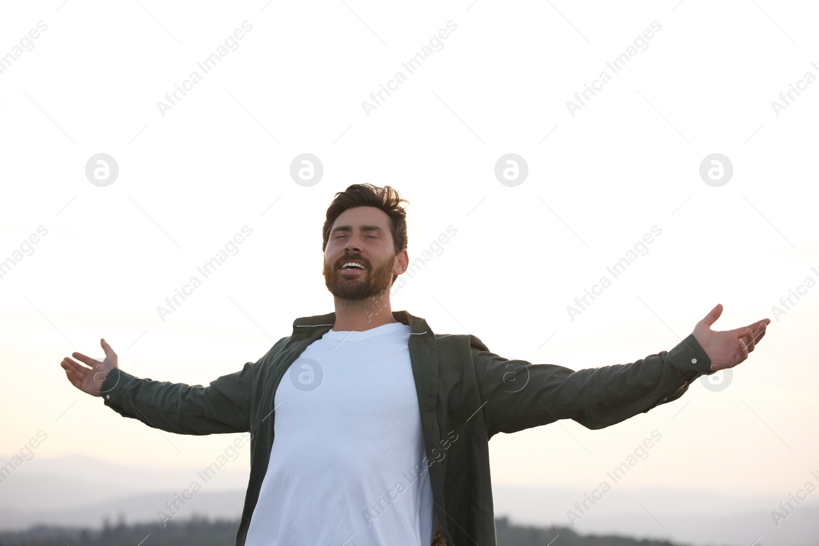 Photo of Feeling freedom. Happy man with wide open arms against sky outdoors
